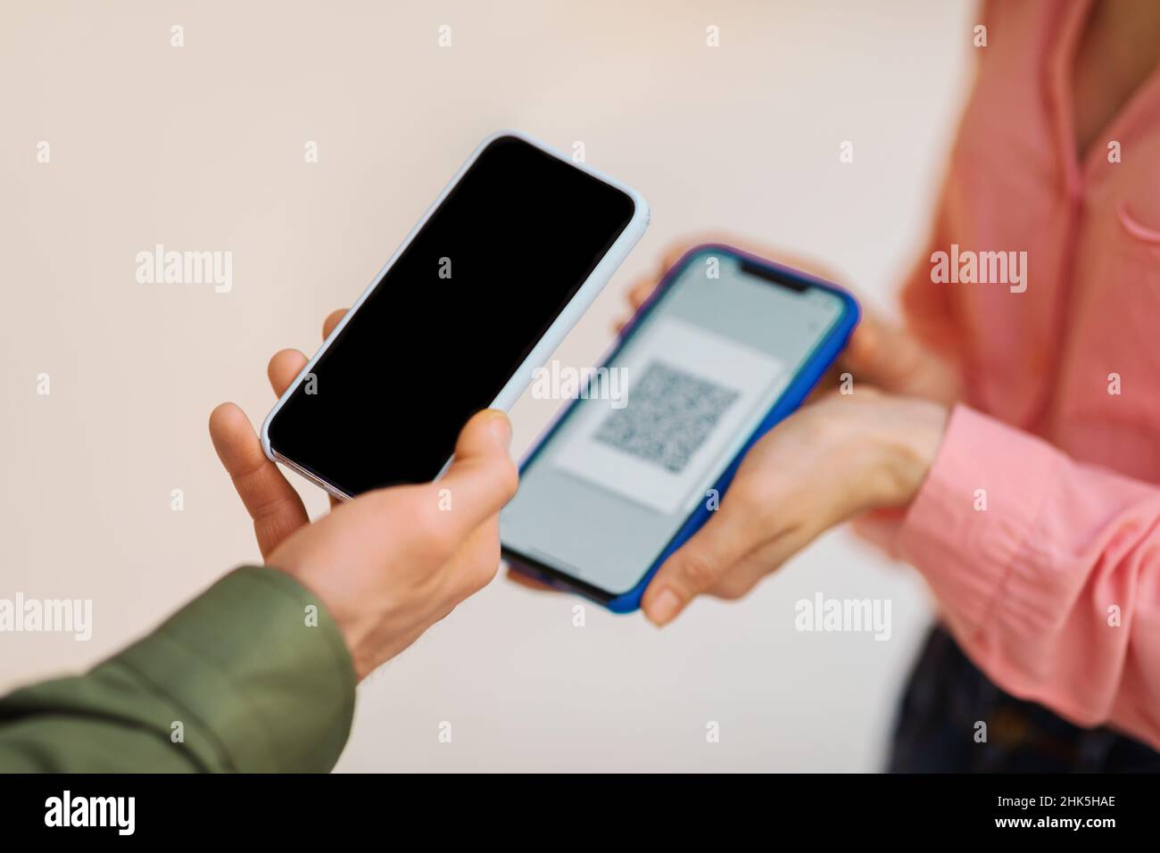 Nicht erkennbarer Mann mit Smartphone Scannen QR-Code auf Lady's Phone Stockfoto