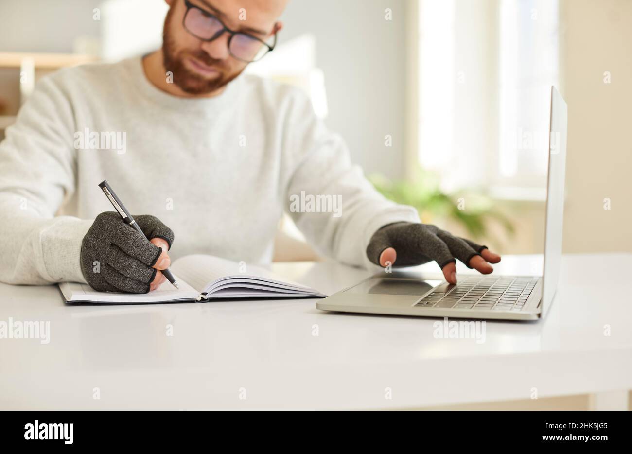 Geschäftsmann in Druckhandschuhen arbeiten am Computer schreiben Notizen Stockfoto