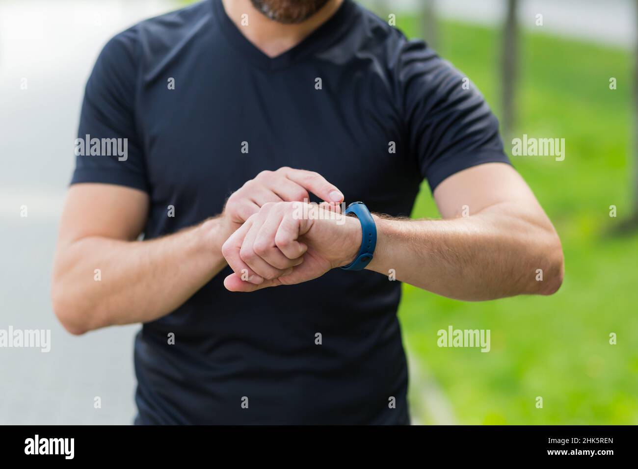 Nahaufnahme der Hände eines männlichen Athleten, der das Fitnessprogramm in der Smart Watch wechselt Stockfoto