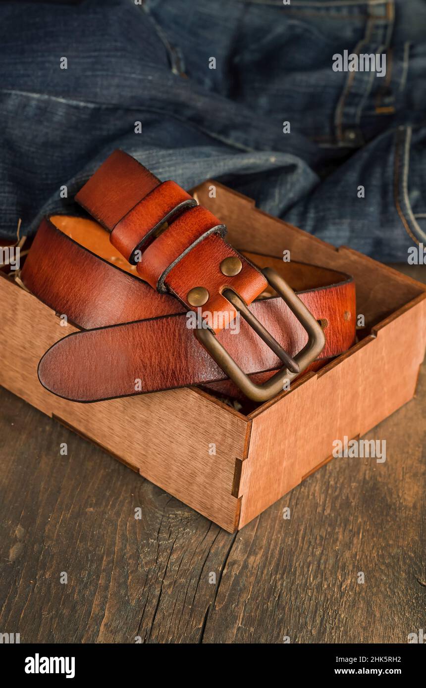 Männer-Leder-Hosengürtel in braun-oranger Farbe auf einem alten Vintage-Holzhintergrund. Stockfoto