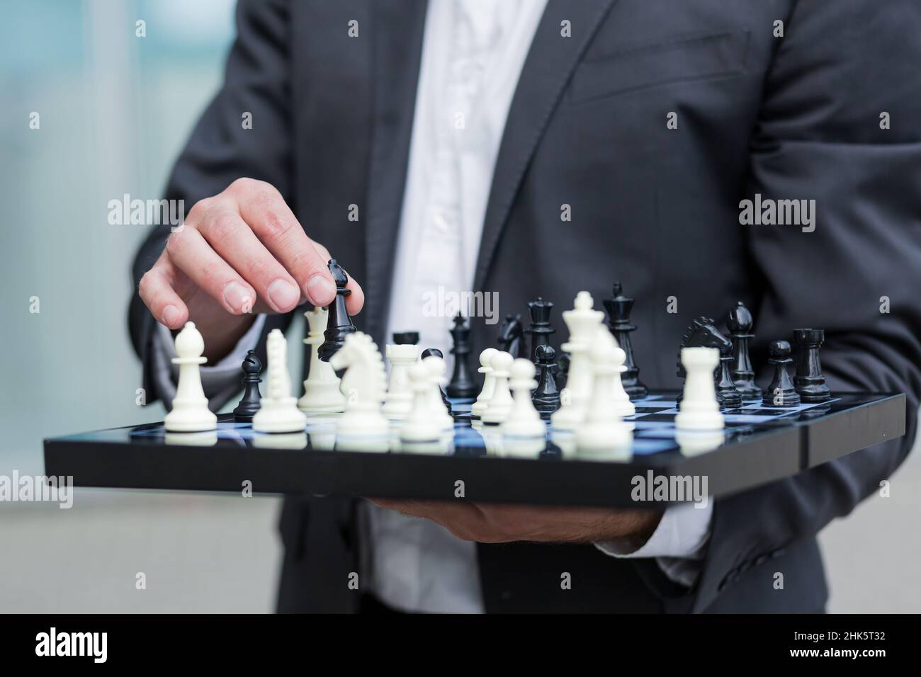 Nahaufnahme eines erfolgreichen Geschäftsmannes, der ein Schachbrett hält und einen Schritt macht Stockfoto