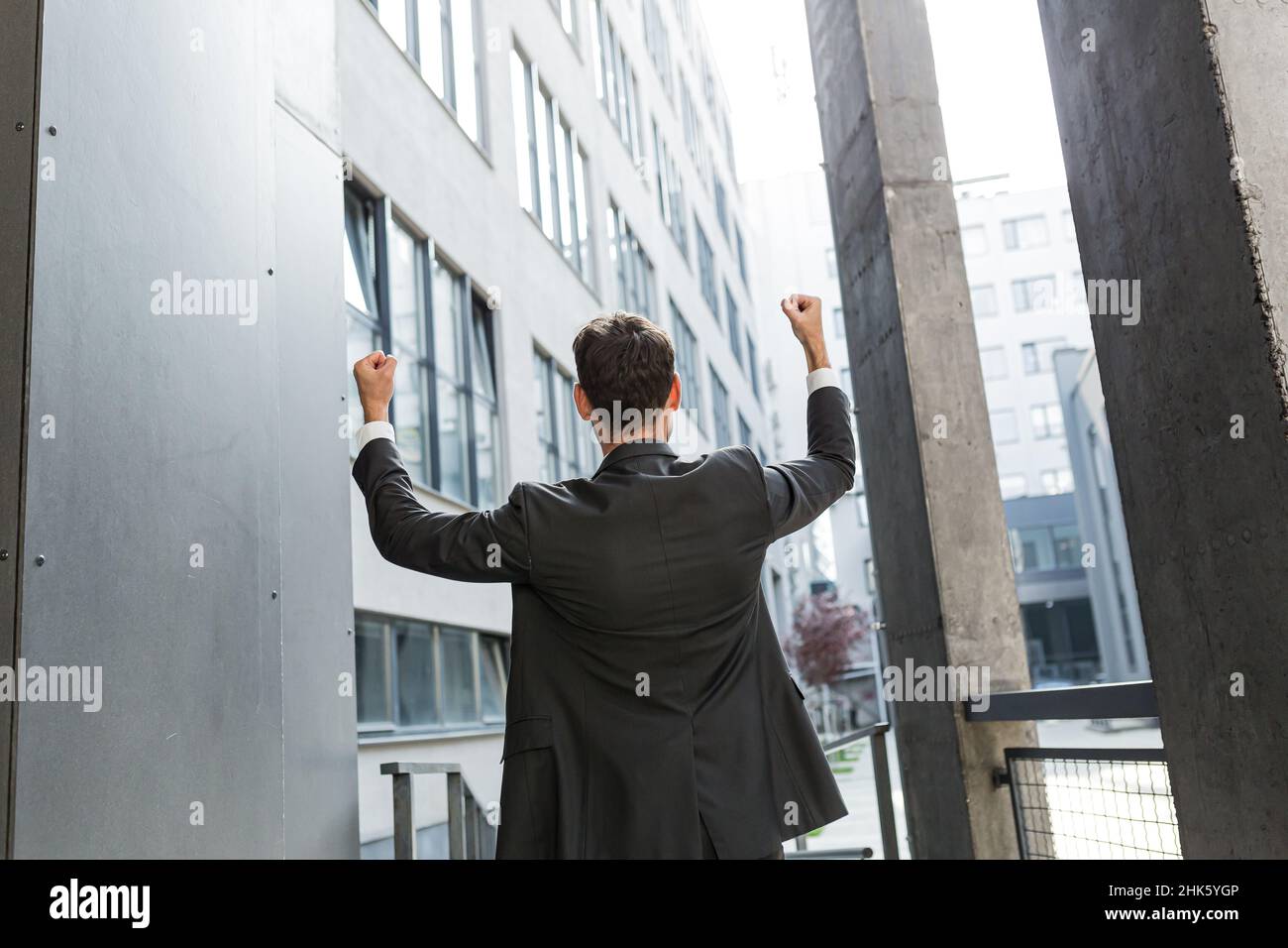 Erfolgreicher kaukasischer Geschäftsmann mit Aufrüstung, der den Sieg feiert. Konzept: Erfolg, Karriereentwicklung, Sieg, Freiheit. Silhouette Business-Mann Mitarbeiter Stockfoto