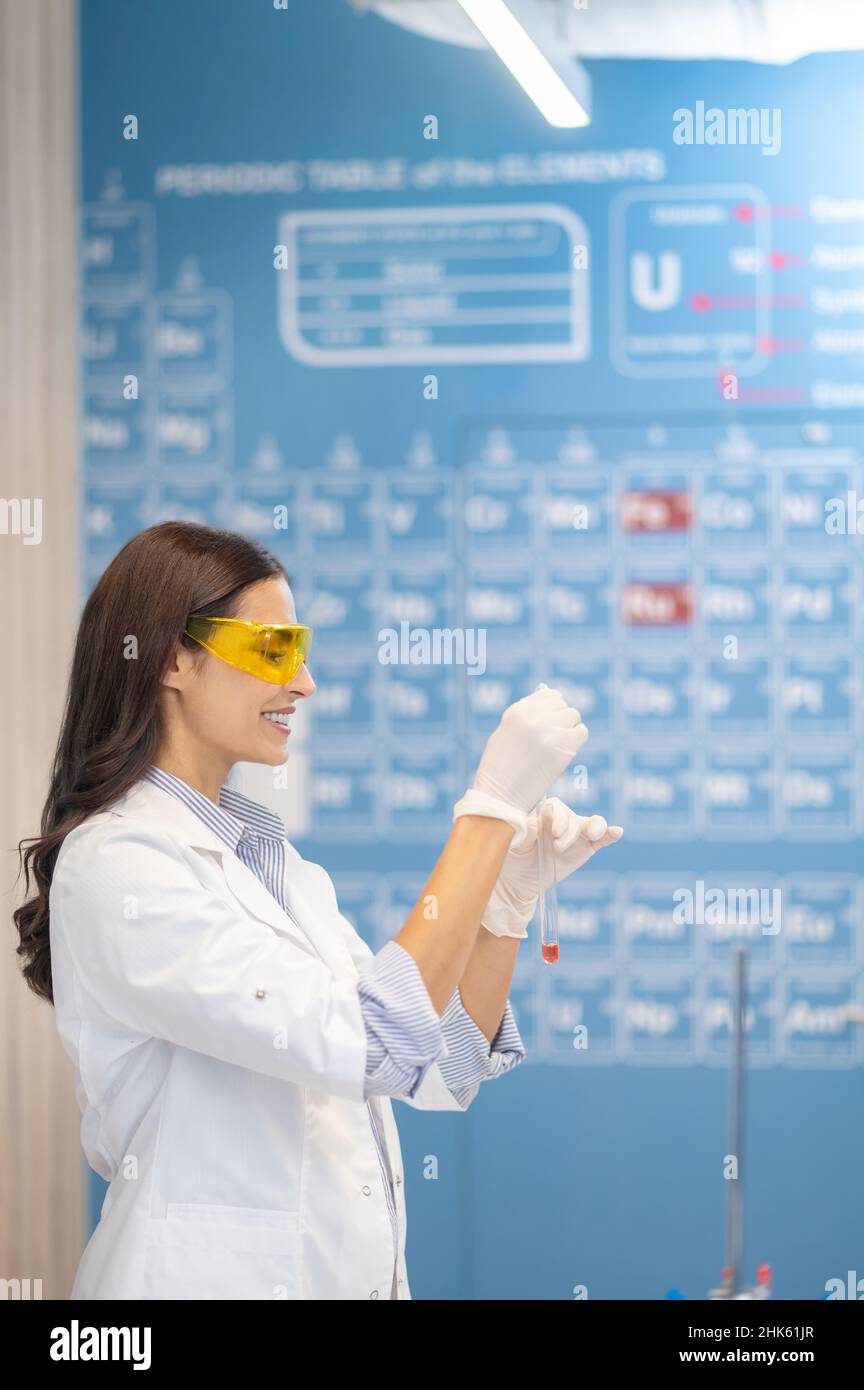 Profil einer Frau in Handschuhen mit Reagenzglas Stockfoto