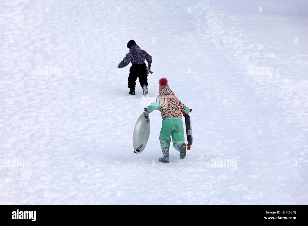 Rodeln im Winterpark, Schneewetter. Kinder klettern auf die Rutsche, um sie herunter zu Rollen Stockfoto