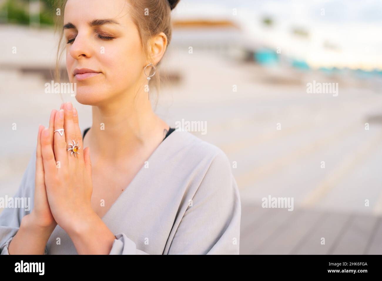 Nahaufnahme einer meditativen jungen Frau, die im Stadtpark Yoga praktiziert und Namaste-Pose mit geschlossenen Augen ausführt. Stockfoto