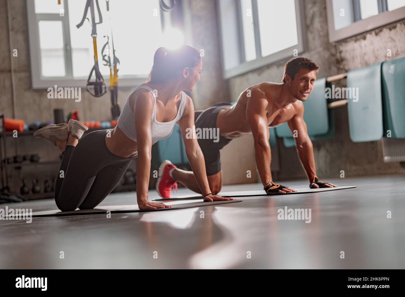 Muskulöser Mann im Fitnessstudio mit einer athletischen Frau, die Sportübungen durchführt Stockfoto