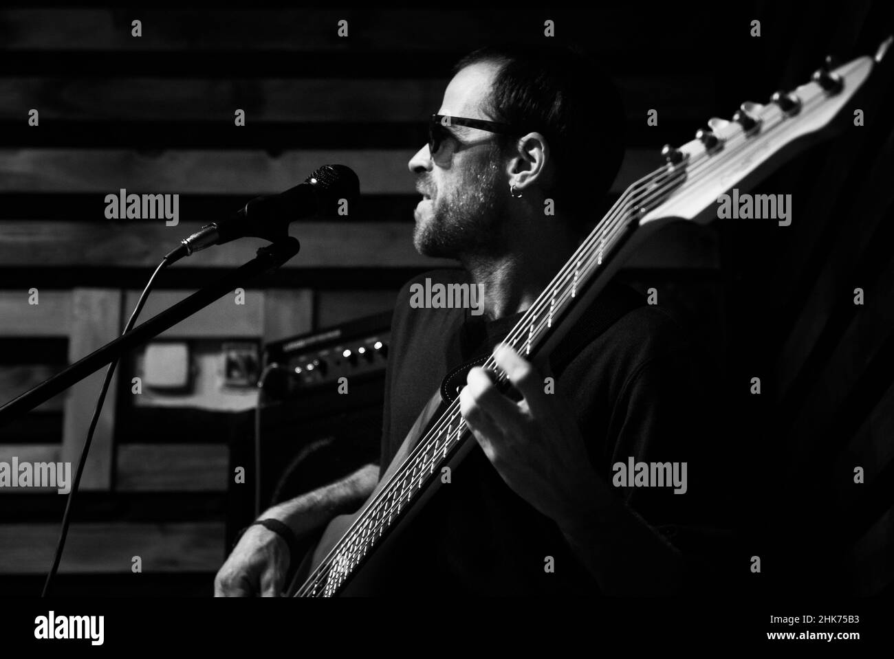 Junger Musiker, der in der Kneipe Gitarre spielt, Graustufen Stockfoto