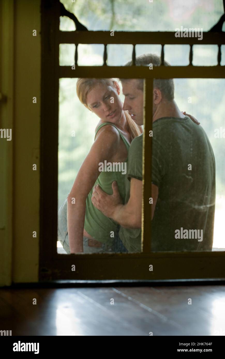 Umarmt junges Paar auf der Veranda, durch die Bildschirmtür gesehen Stockfoto