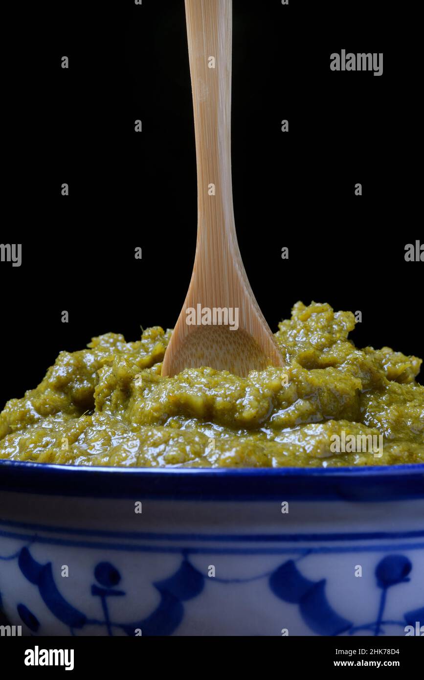 Grüne Thai-Schälpaste in Schüssel mit Holzlöffel Stockfoto