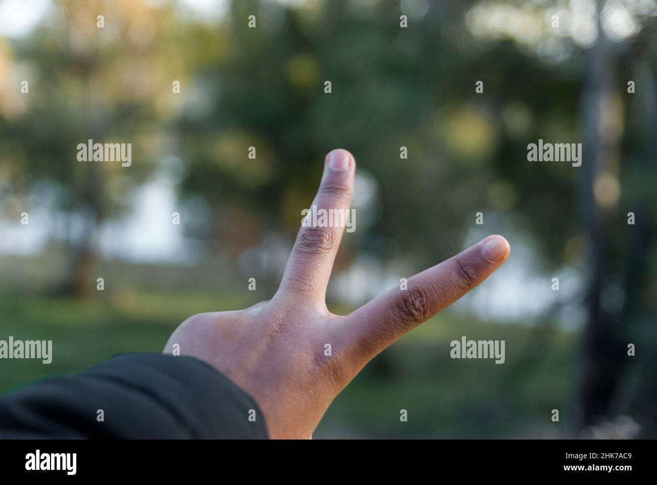 Zeichen des Sieges mit den Fingern der Hand mit einem unfokussierten Hintergrund und Bereich für Text oder Kopierraum Stockfoto