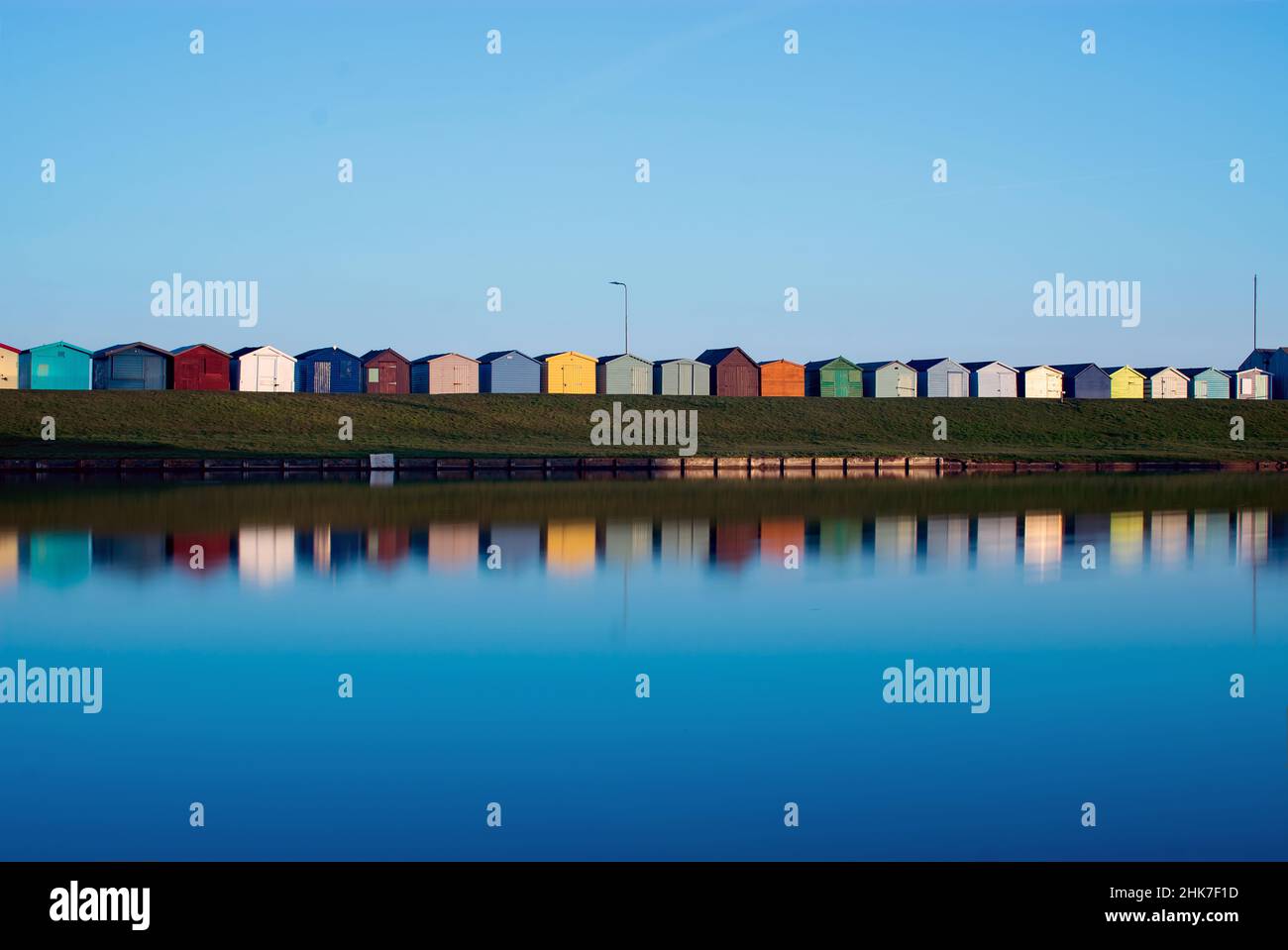 Farbenfrohe Strandhütten aus Holz säumen den Hügel entlang der Ränder des Dovercourt Bootssees entlang der North Essex Coast. Harwich & Dovercourt, England, Großbritannien Stockfoto