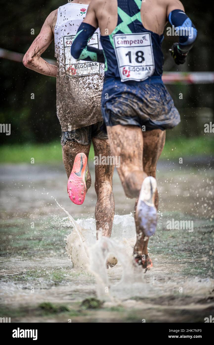 Die Beine des Athleten laufen in einem Cross Country zwischen Wasser und Schlamm, Pure Cross. Stockfoto