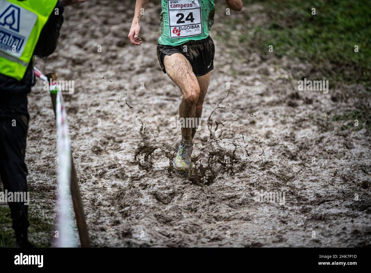 Die Beine des Athleten laufen in einem Cross Country zwischen Wasser und Schlamm, Pure Cross. Stockfoto