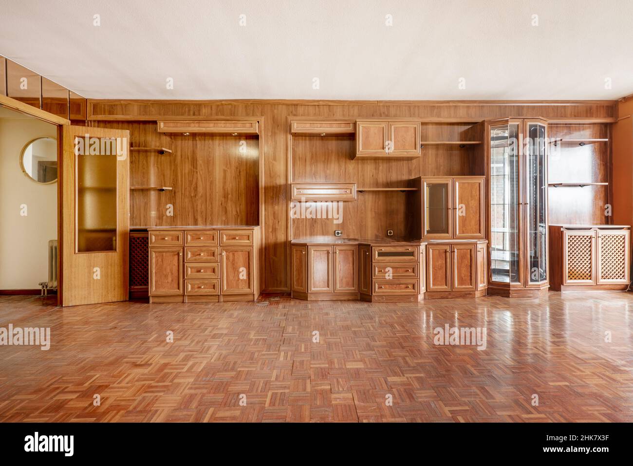 Geräumiges Zimmer mit Holzgemälden, die eine Wand mit Parkett in passender Farbe bedecken Stockfoto