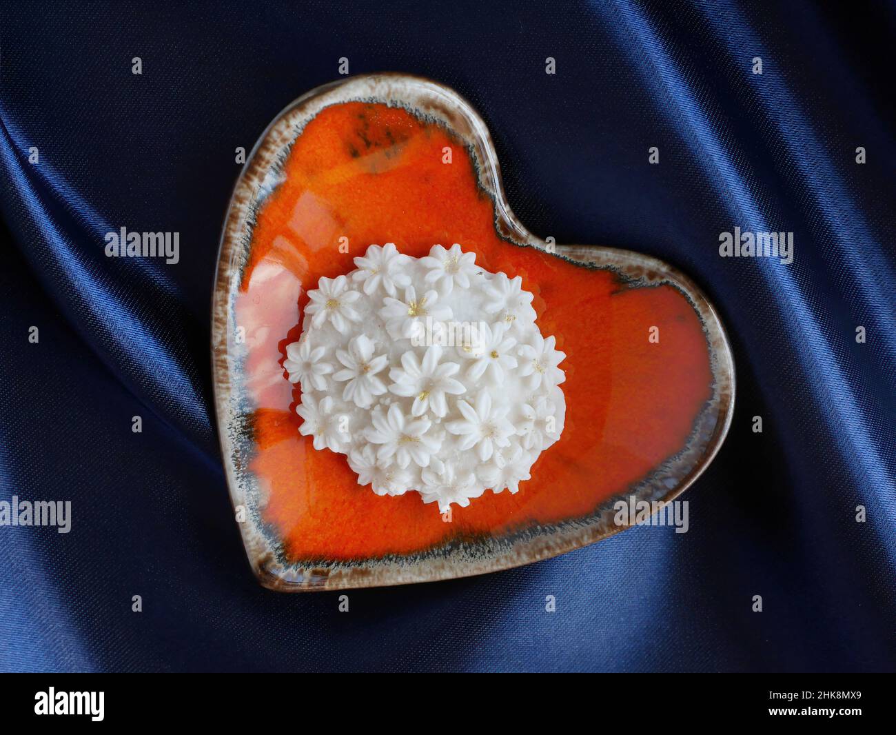 Nahaufnahme von Sam Pan Nee Thai Traditional Dessert Handcraft Royal Famous thai Snack in orange Herzform Teller mit blauem Satin Hintergrund valentine Stockfoto