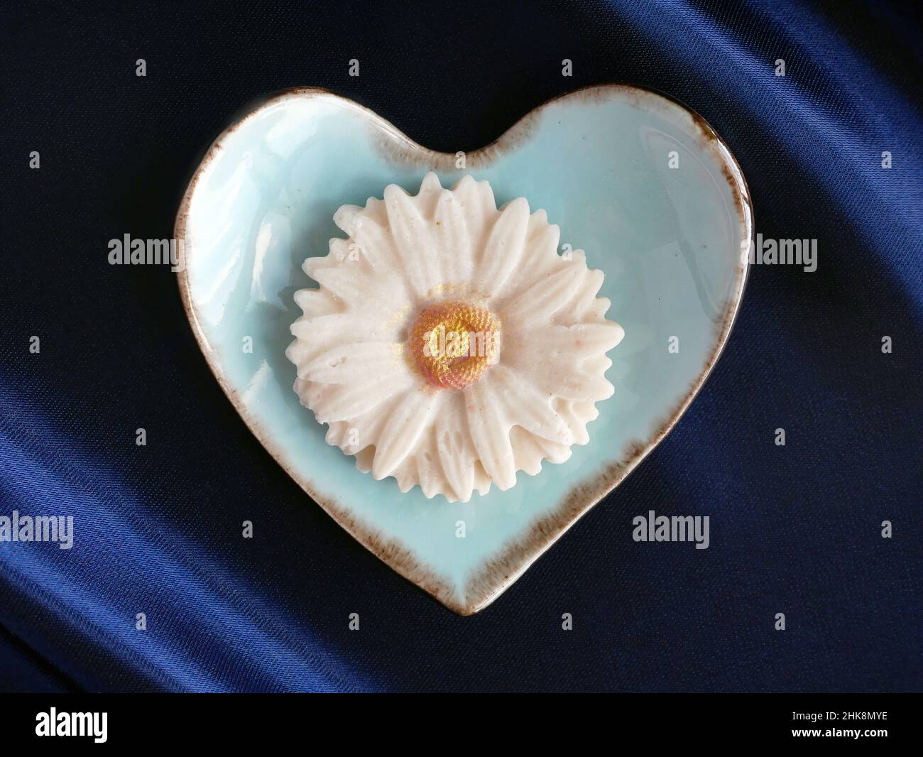 Draufsicht auf Sam Pan Nee Thai Traditional Dessert Handcraft Royal Famous thai Snack in pastellblauem Herzform Teller mit blauem Satin Hintergrund Stockfoto