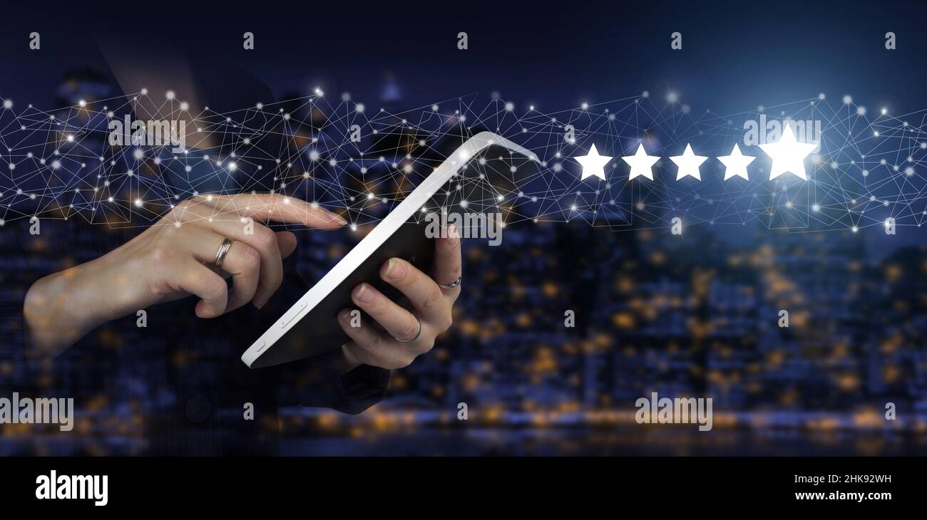 Umfrage zur Unternehmenszufriedenheit. Weißes Tablet mit Handberührung und digitalem Hologramm, fünf Sterne auf dunklem, unscharfem Hintergrund der Stadt. Bewertung, Bewertung, Satisfacti Stockfoto