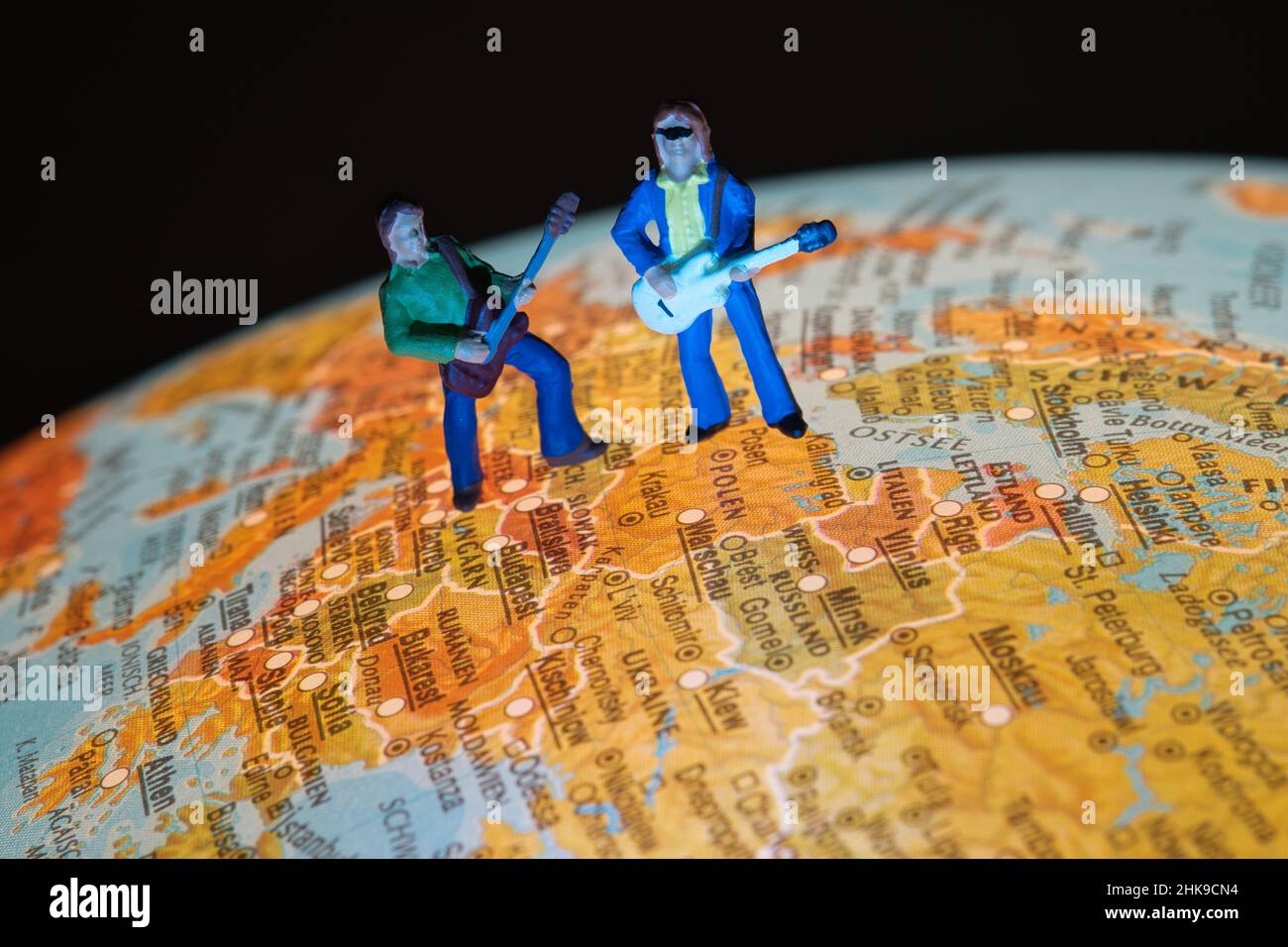 Zwei Miniaturmusiker mit Gitarre stehen auf einem Globus in der europäischen Region Stockfoto