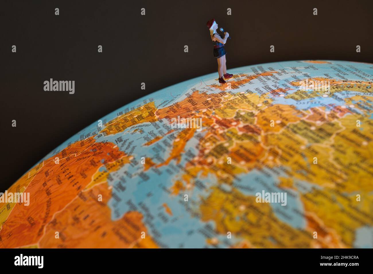 Miniatur-Sängerin mit Mikrofon auf einem Globus, in der Region Europa, England Stockfoto