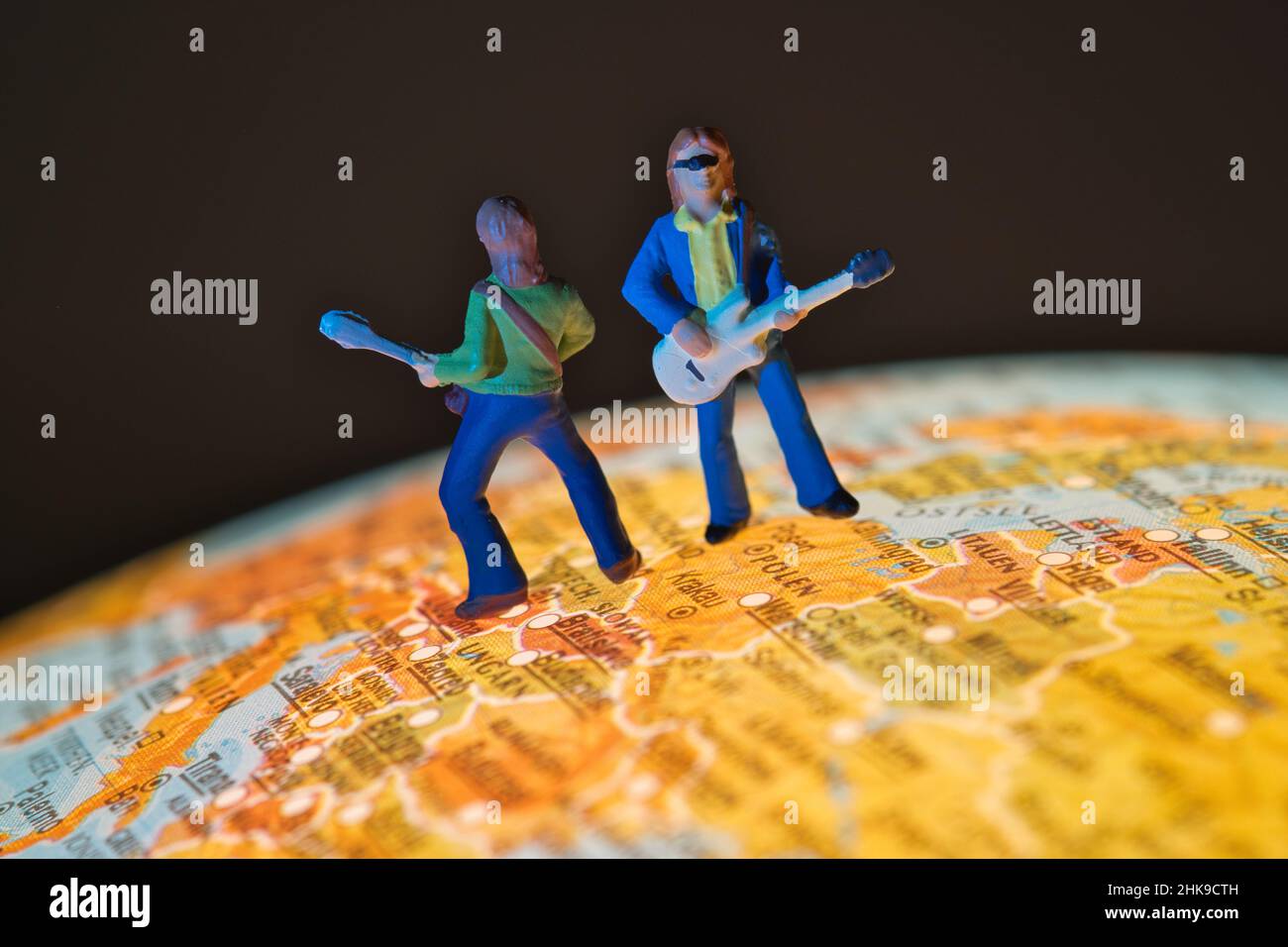 Nahaufnahme von zwei Miniaturmusikern mit einer Gitarre, die auf einem Globus in der europäischen Region stehen Stockfoto