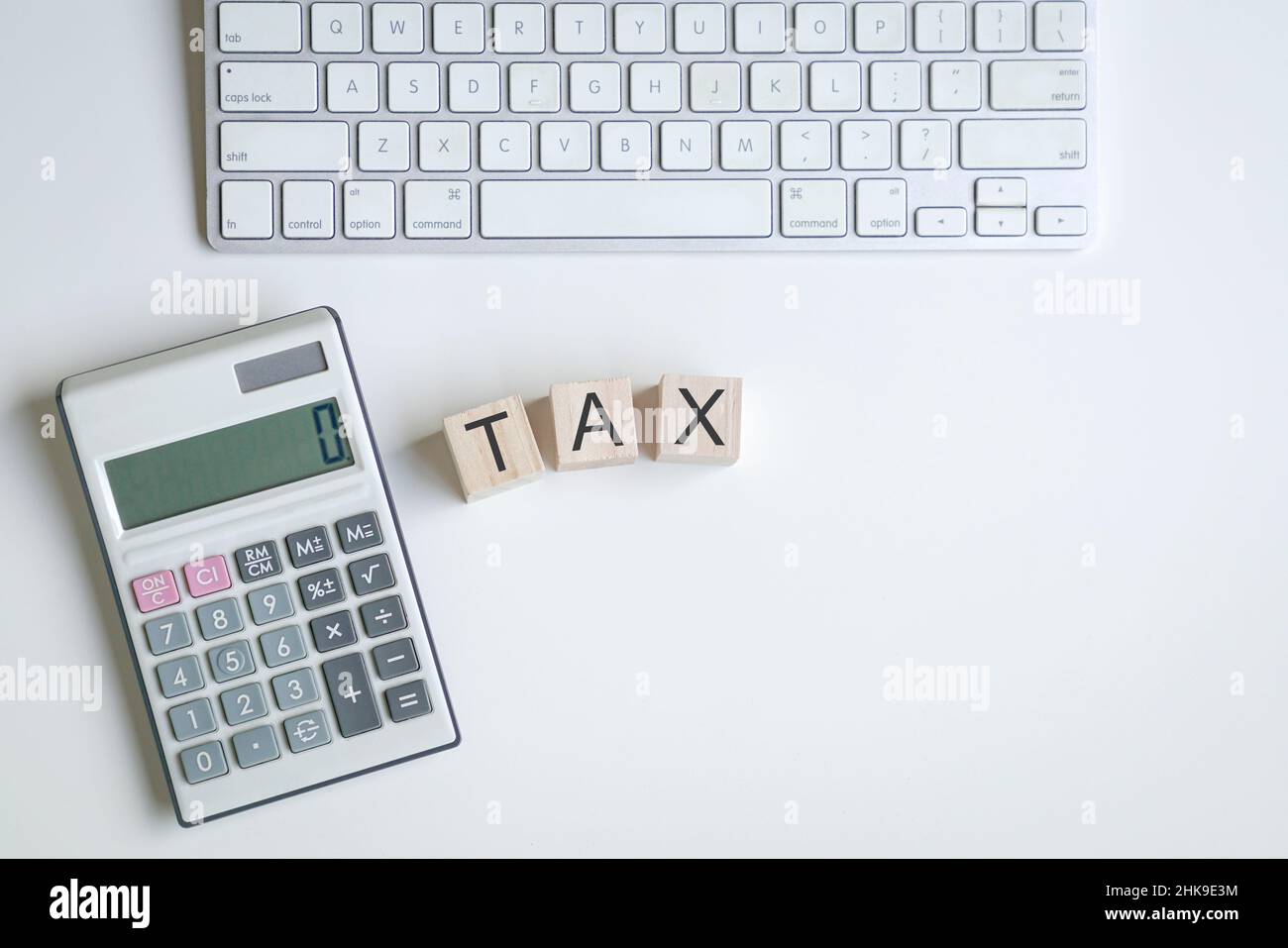 Das Wort Tax auf Holzwürfeln neben Rechner und Tastatur. Konzept der Steueranmeldung. Stockfoto