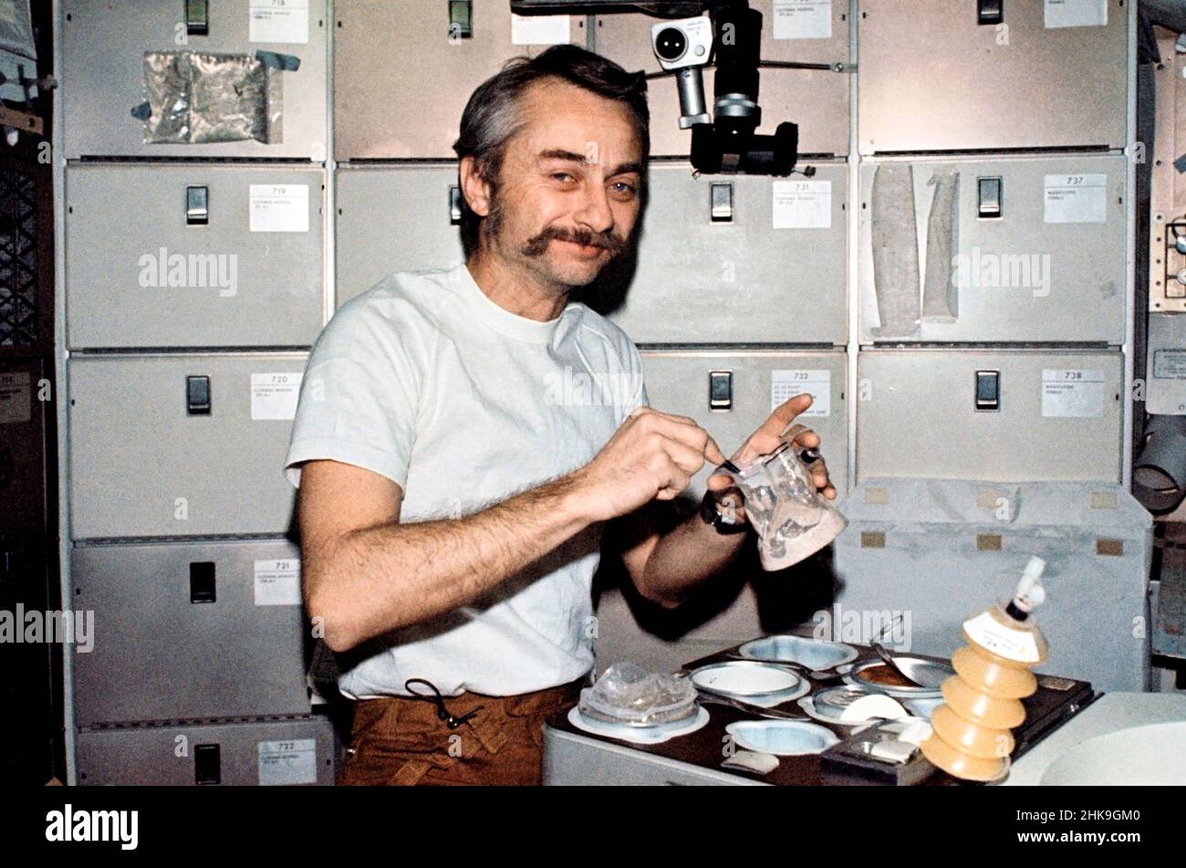 (6. August 1973) --- Wissenschaftler-Astronaut Owen K. Garriott, Wissenschaftspilot Skylab 3, rekonstituiert einen vorverpackten Behälter mit Lebensmitteln am Stationszimmertisch des Orbital Workshop (OWS) des Skylab Space Station Clusters. Dieses Bild wurde mit einer handgehaltenen Nikon-Kamera 35mm aufgenommen. Die Astronauten Garriott, Alan L. Bean und Jack R. Lousma blieben insgesamt 59 Tage lang bei der Skylab-Raumstation in der Erdumlaufbahn und führten zahlreiche medizinische, wissenschaftliche und technische Experimente durch. Beachten Sie das Messer und die Gabel auf dem Tablett und das Utensil, mit dem Garriott das mit Wasser vermischte Essen rührt Stockfoto
