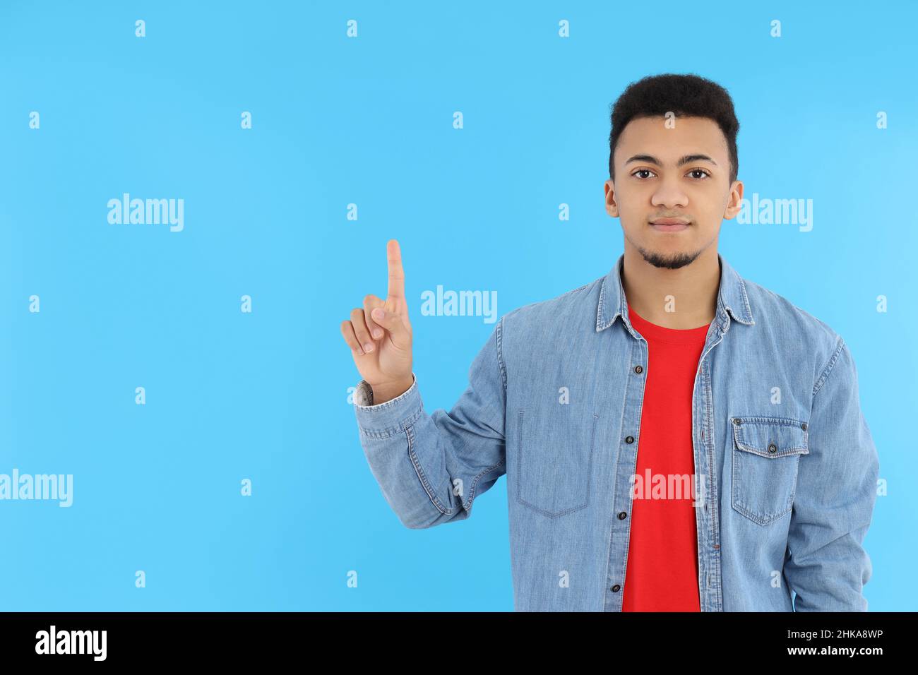 Junger Mann in Jeans-Hemd auf blauem Hintergrund Stockfoto