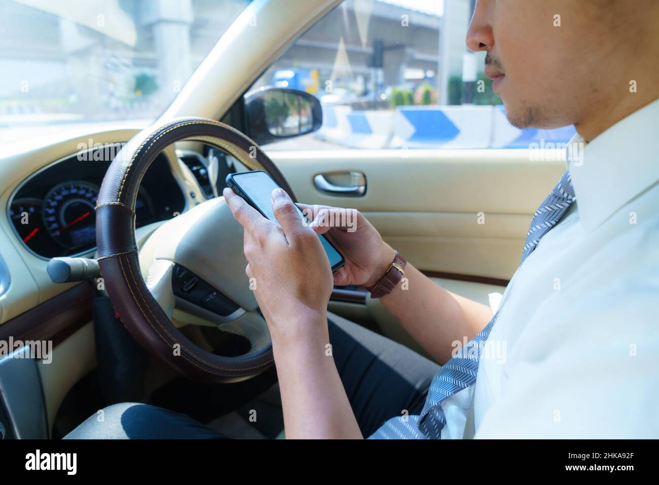 Auto fahren und Telefon benutzen. Abgelenkt Fahrer SMS mit Handy. Unverantwortlicher Mann, der im Verkehr mit dem Smartphone Nachrichten überprüft. Autom. Akzi Stockfoto