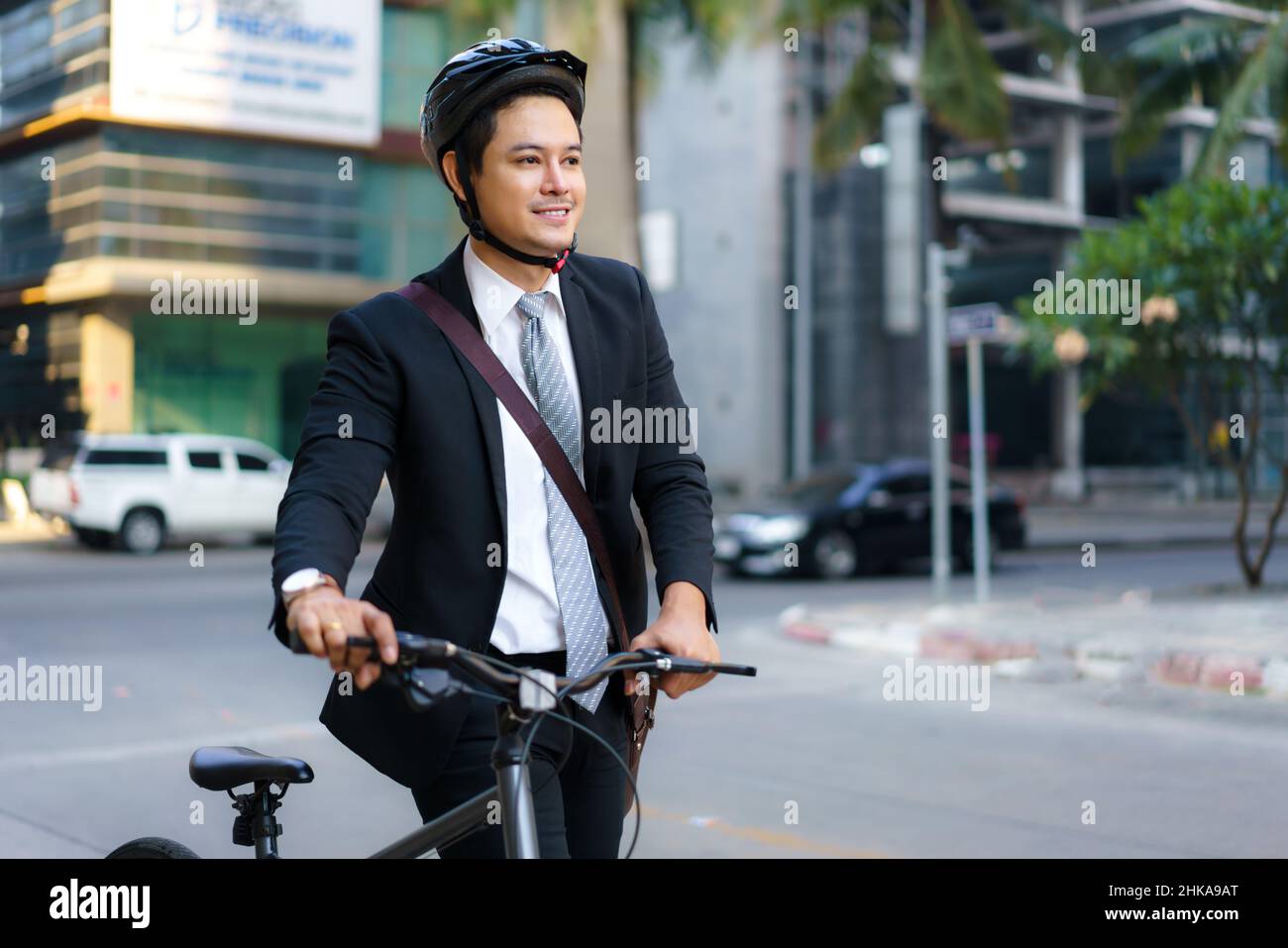 Ein asiatischer Geschäftsmann schiebt morgens sein Fahrrad von zu Hause und bereitet sich darauf vor, mit dem Fahrrad zur Arbeit zu fahren. Umweltfreundlicher Transport. Stockfoto