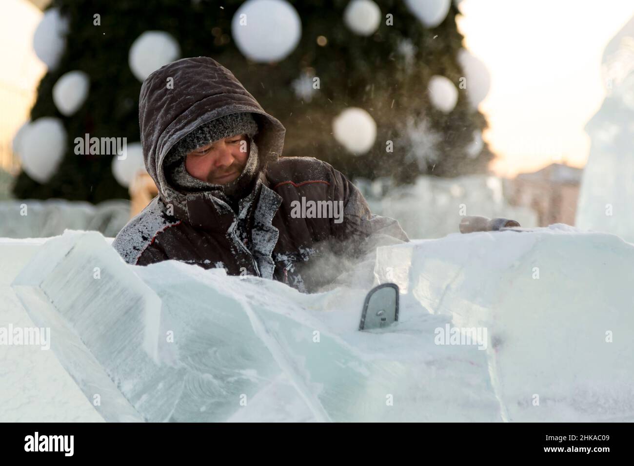 Der Bildhauer schneidet ein Eis Abbildung aus Eis durch eine Kettensäge für Weihnachten Stockfoto