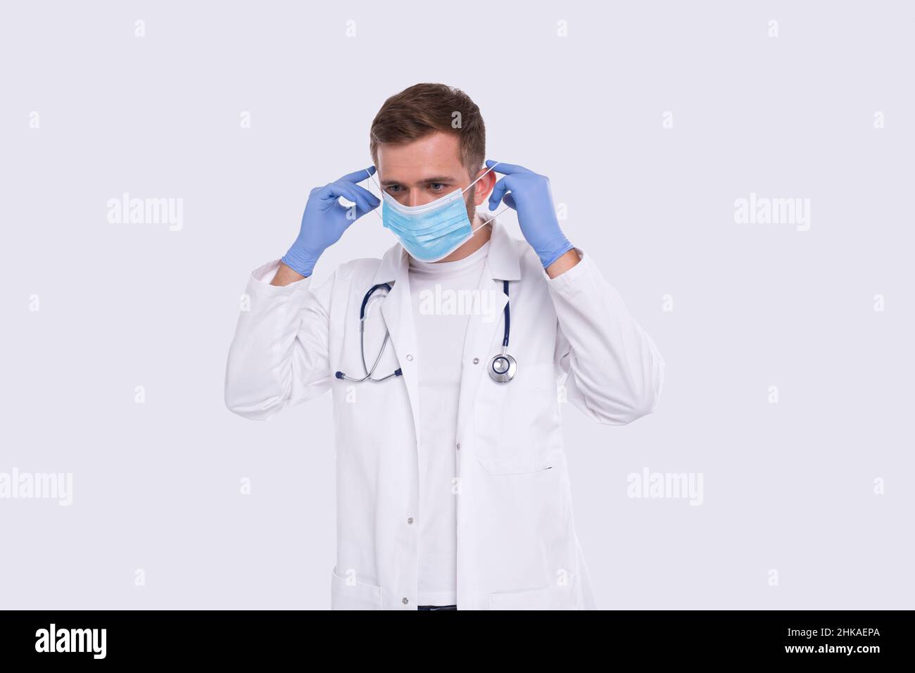 Arzt zieht medizinische Maske an und trägt Handschuhe. Medizinische Arbeitskleidung Für Ärzte. Medizinisches Konzept. Arzt Mit Medizinischer Maske Stockfoto