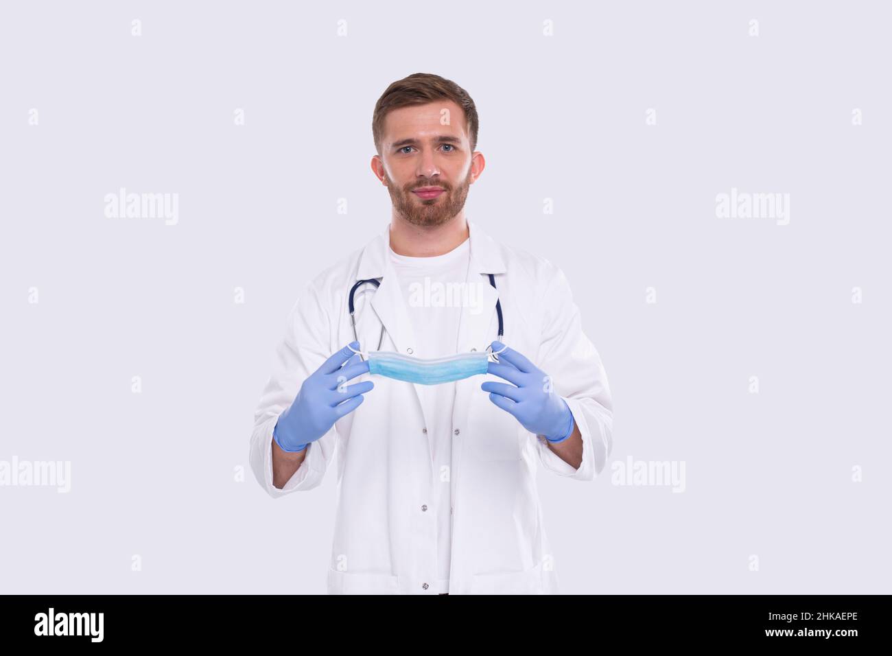 Arzt zieht medizinische Maske an und trägt Handschuhe. Medizinische Arbeitskleidung Für Ärzte. Medizinisches Konzept. Arzt Mit Medizinischer Maske Stockfoto