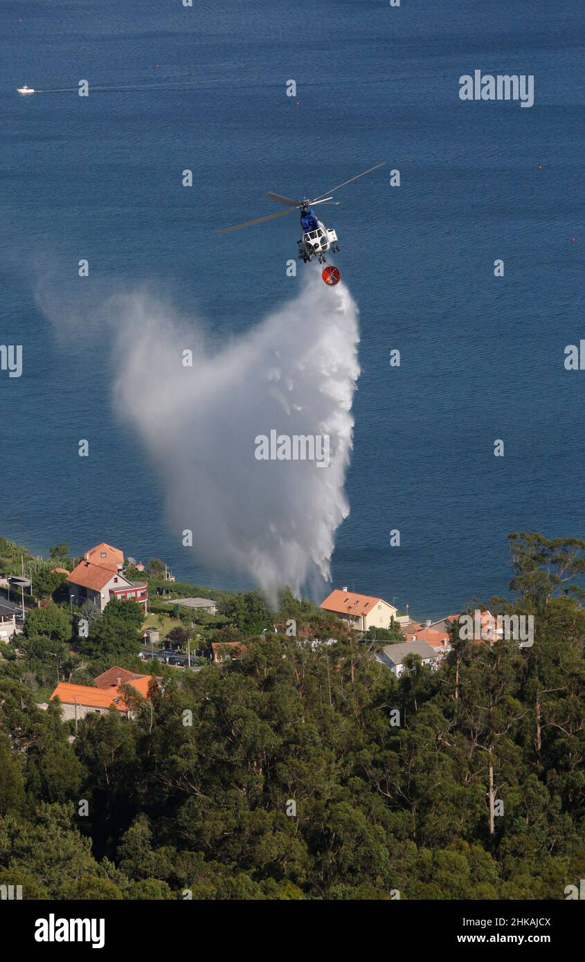 Ein Feuerwehrhubschrauber wirft Wasser auf einen Waldbrand Stockfoto