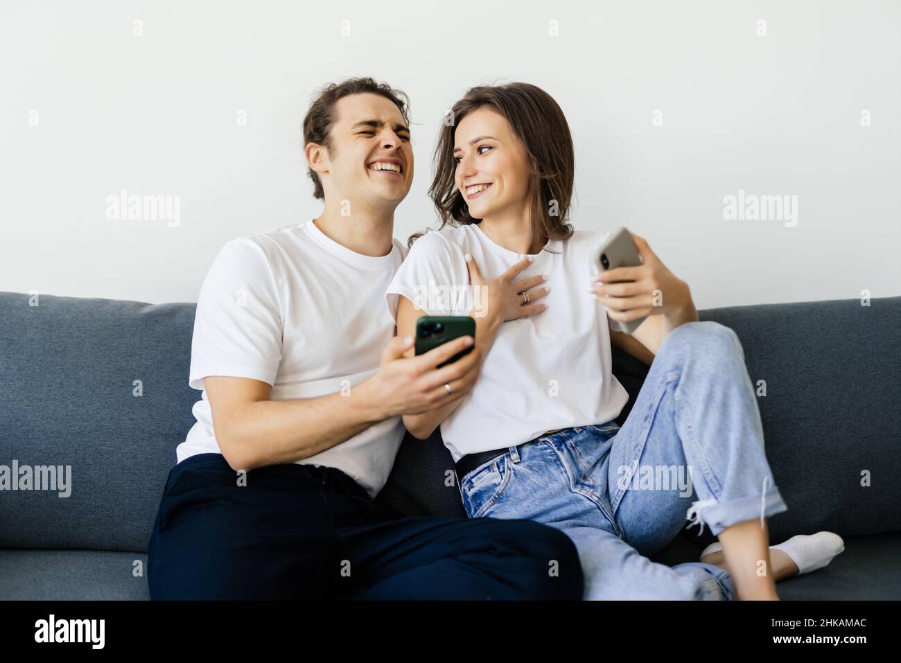 Mobile Suchtkonzept, junges Paar mit Smartphones auf dem Sofa entspannen, Millennial Mann und Frau besessen von neuen Apps oder sozialen Netzwerken, Telefon A Stockfoto