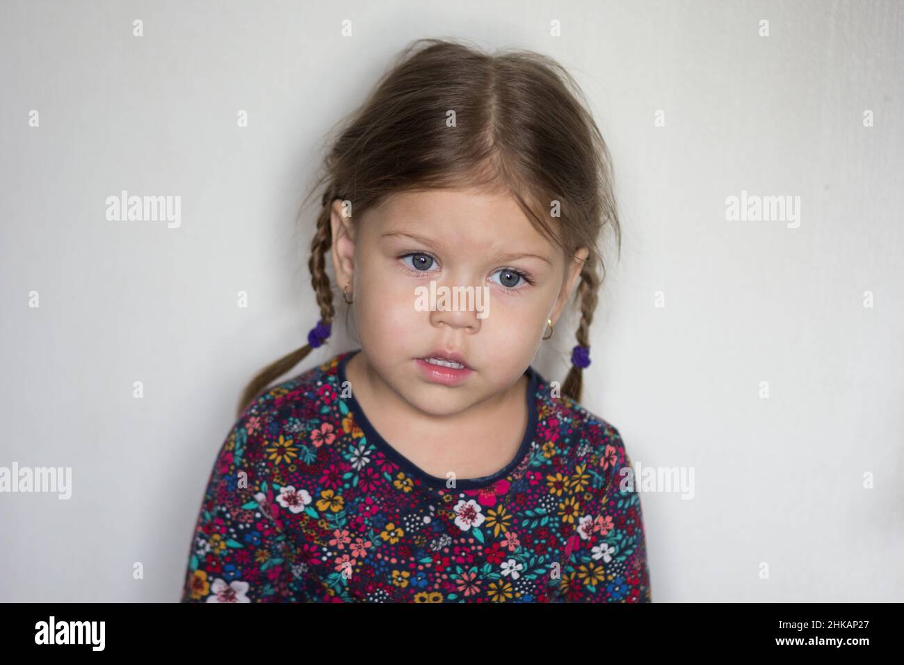 Porträt des Kaukasiers eines dreijährigen kleinen Mädchens in einem Verlust, das auf dem weißen Hintergrund zur Seite schaut Stockfoto
