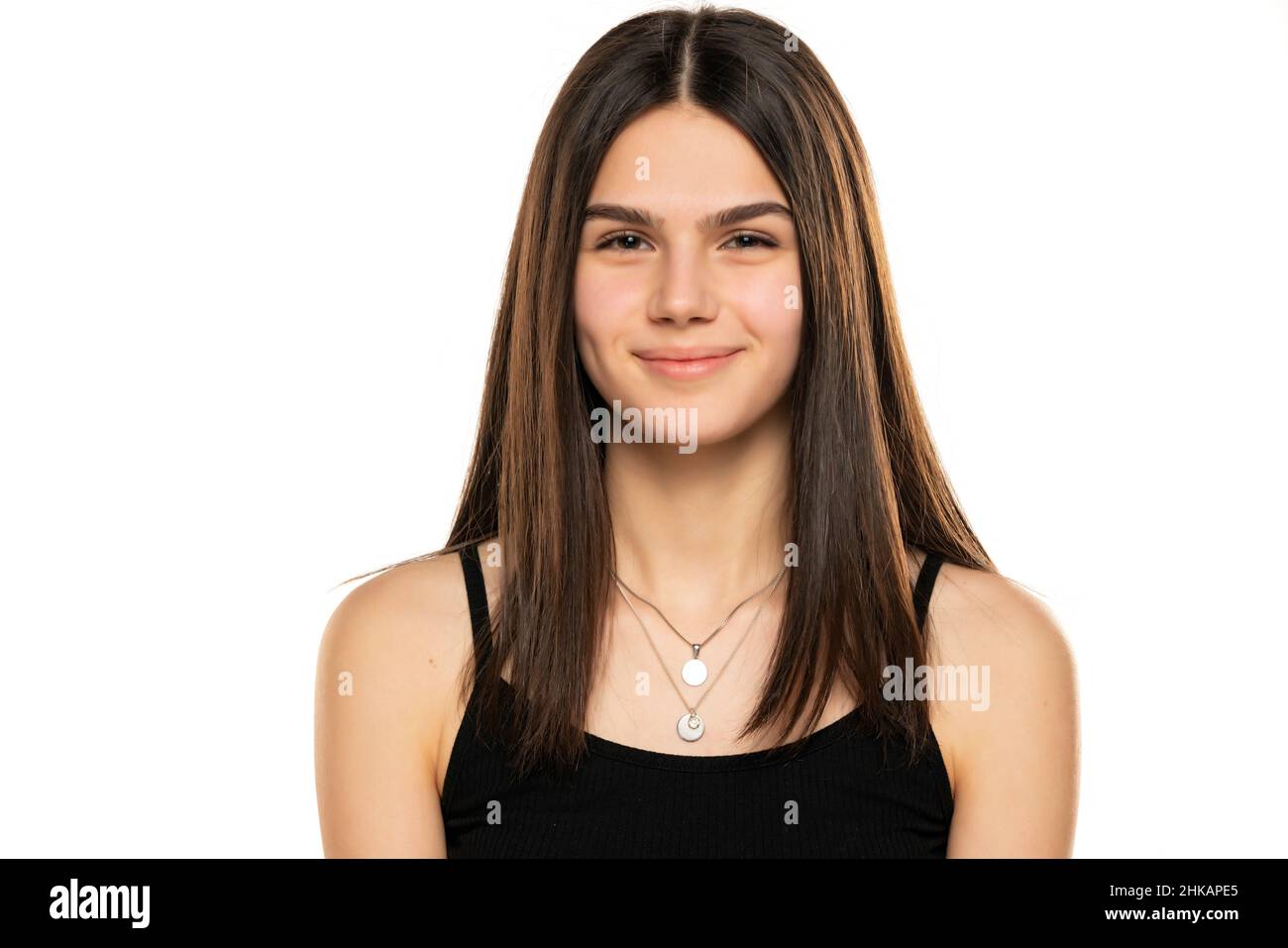 Porträt eines schönen lächelnden Teenager-Mädchen mit langen geraden Haaren und kein Make-up auf weißem Hintergrund Stockfoto