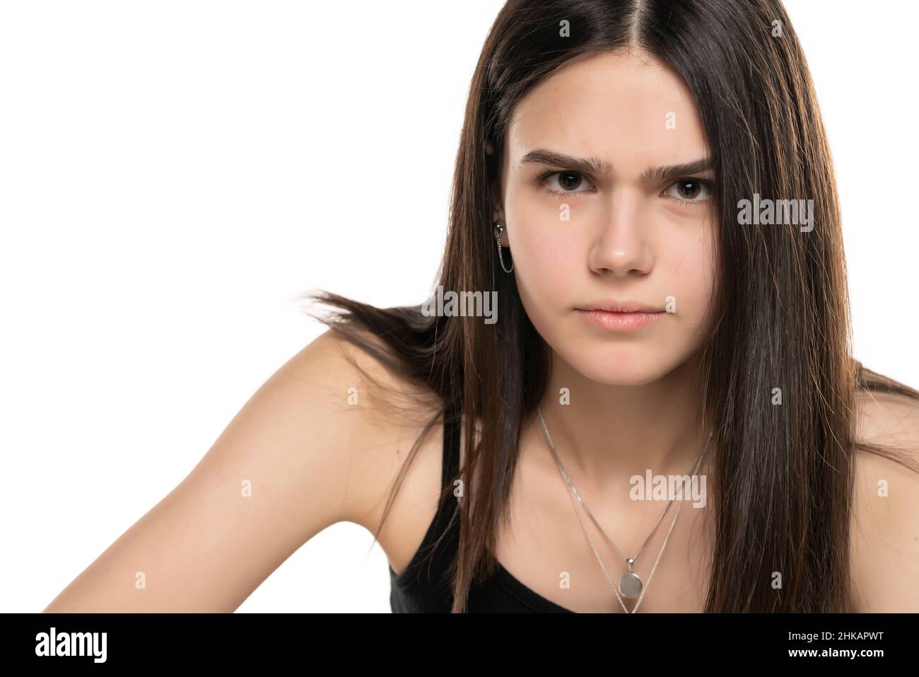 Portrait eines verärgerten Teenagers mit langen, geraden Haaren und ohne Make-up auf weißem Hintergrund Stockfoto