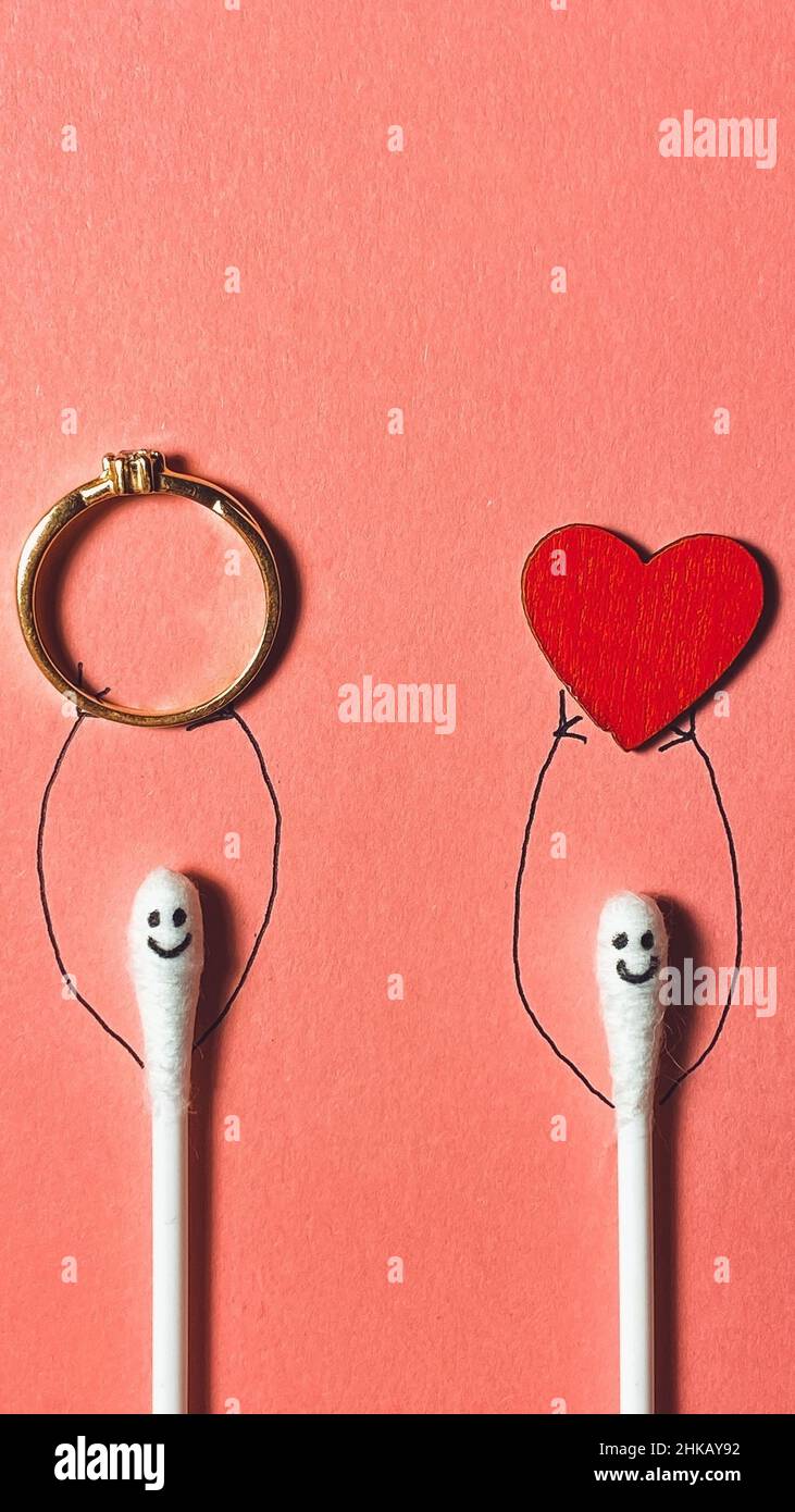 In die Liebe verliebte Baumwollknospen mit gezogenen Händen halten ein Herz und einen Ehering, das Konzept der Liebe und des valentinstags Stockfoto