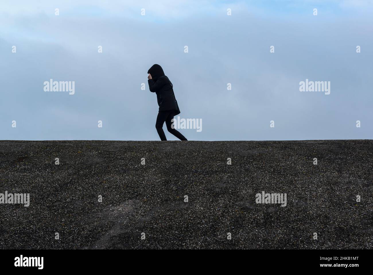 Frau, die am 31 2022. Januar im Sturm Corrie auf einem Deich am Oosterscheldekering (Ostschelde-Sturmflutwehr) spazierend ist. Zeeland, Niederlande Stockfoto