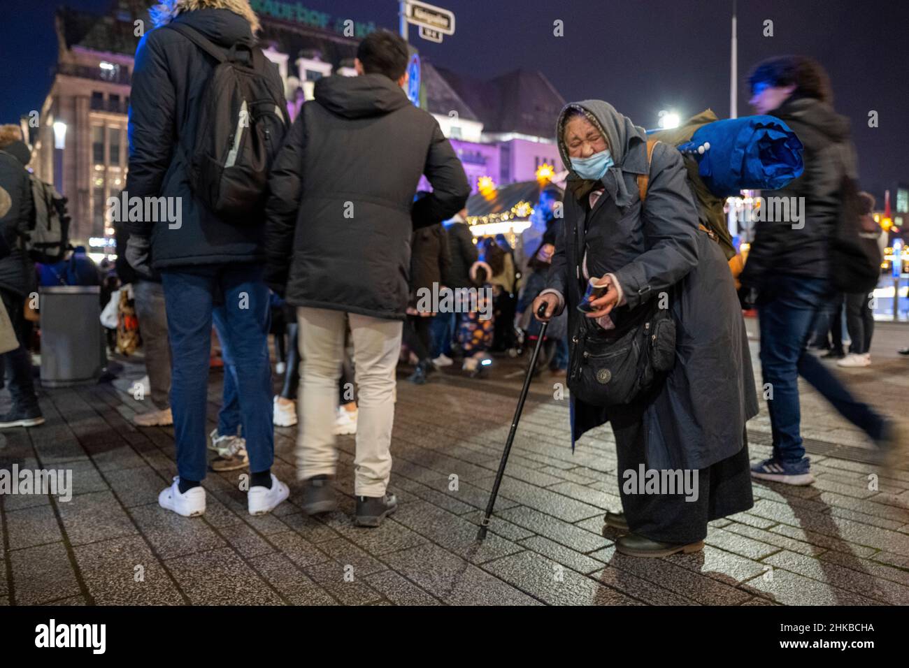 Auf der Königsallee in der Düsseldorfer Innenstadt, NRW, kommen am 11.12.2021 Käufer an einer Frau vorbei, die um Geld bettelt Stockfoto