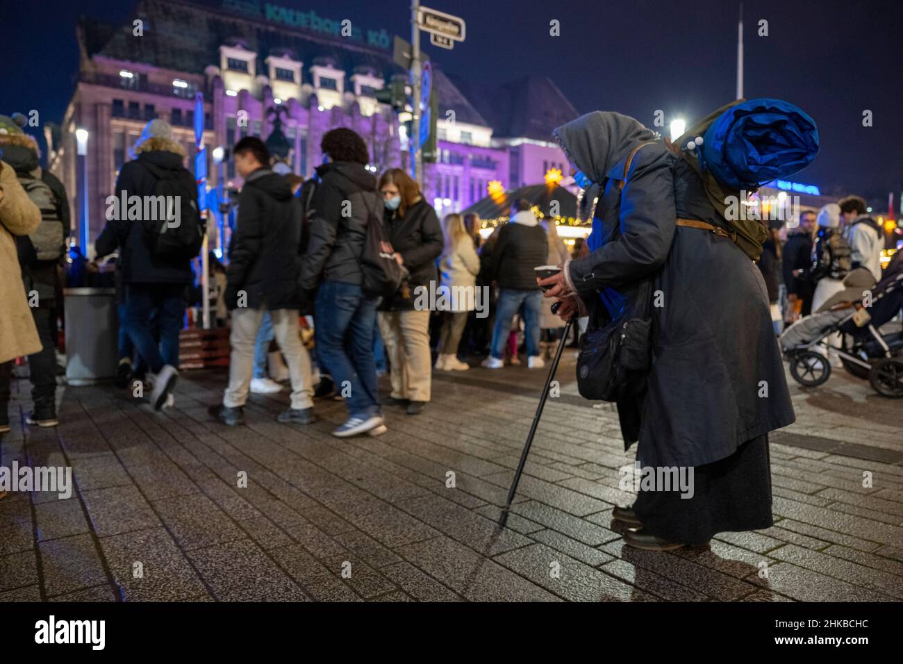 Auf der Königsallee in der Düsseldorfer Innenstadt, NRW, kommen am 11.12.2021 Käufer an einer Frau vorbei, die um Geld bettelt Stockfoto