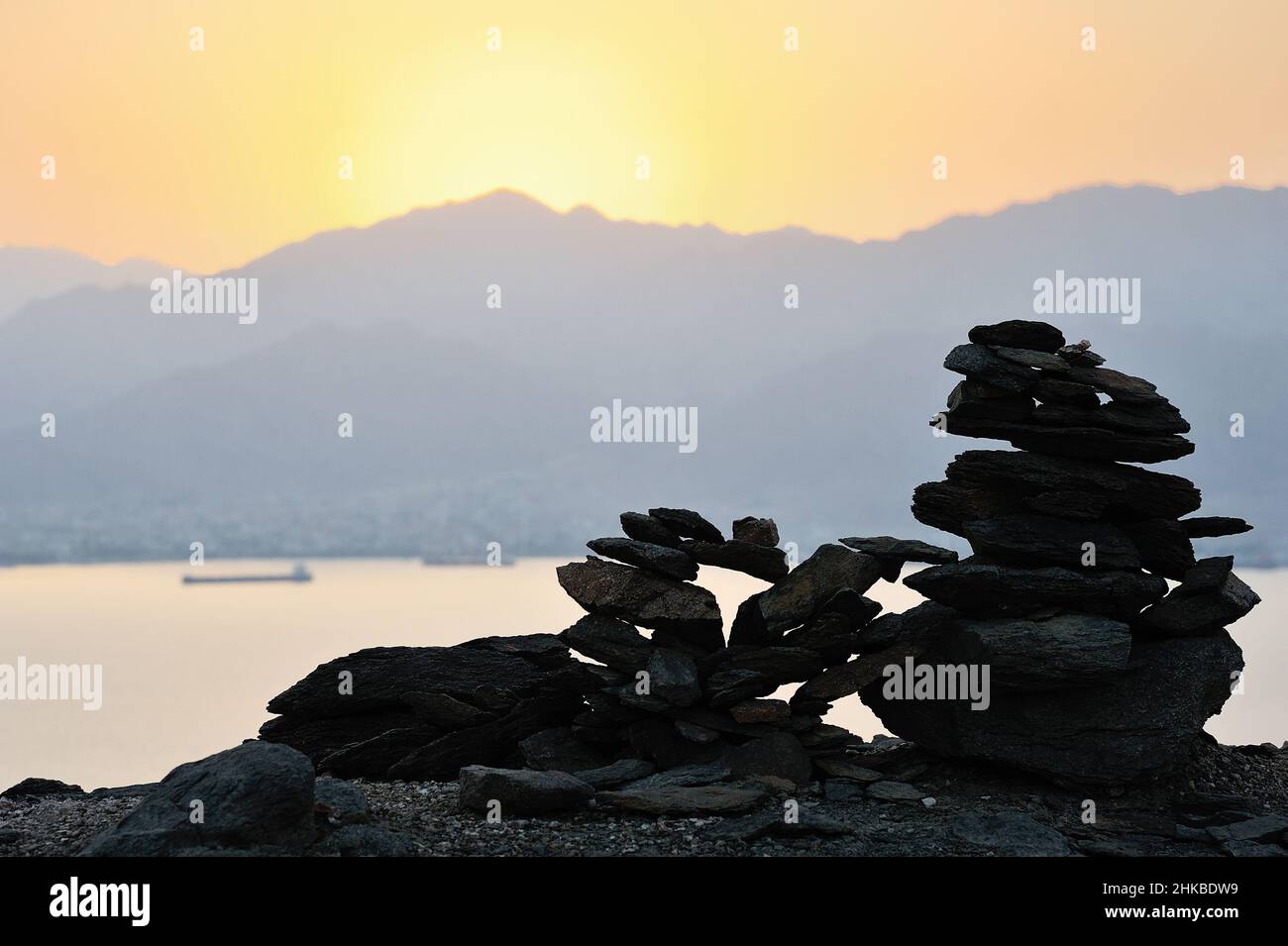 Silhouette einer Pyramide aus flachen Steinen vor dem Hintergrund eines Sonnenuntergangs in den Bergen Stockfoto