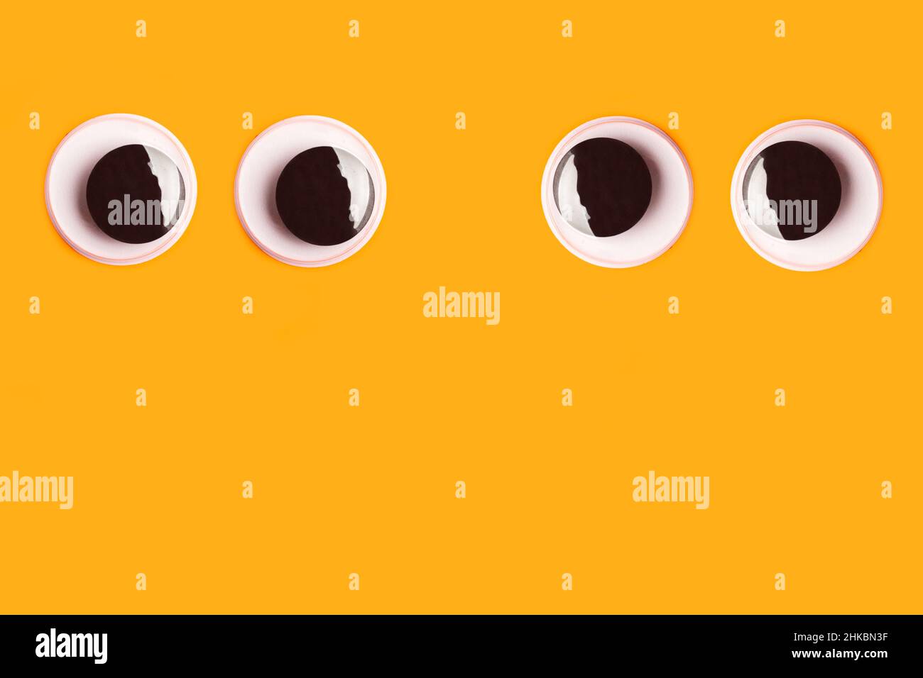 Ein Paar schöne Augen auf einem orangefarbenen Hintergrund mit Kopierfläche Stockfoto