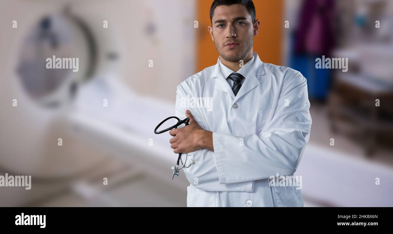 Porträt eines selbstbewussten birazialen männlichen Arztes mit gekreuzten Armen, die gegen den mrt-Scanner stehen Stockfoto