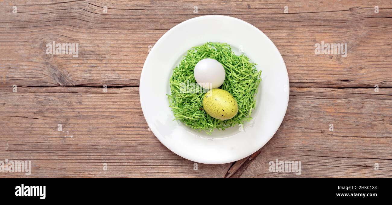 Ostern Tischfeier. Eiernest Dekoration in einer weißen Schale, Holztisch Hintergrund, Draufsicht, Kopierraum. Frühlingsurlaub Stockfoto