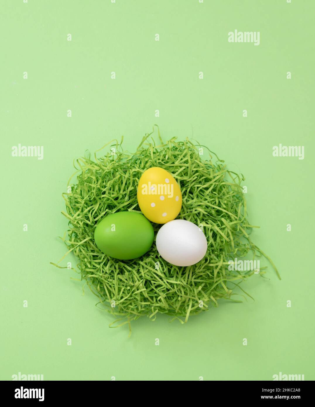 Ostereier im Nest, pastellgrüner Hintergrund, Draufsicht. Frühlingsfeiertage, Platz kopieren. Stockfoto