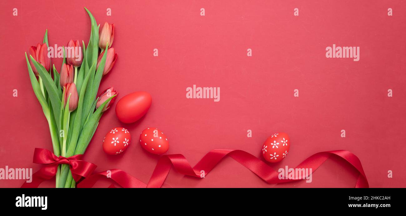 Osterdekoration. Rotes Ei, frisches Tulpenstrauß und Satinband, Draufsicht. Christliche Religion Frühlingsfeiertage. Stockfoto