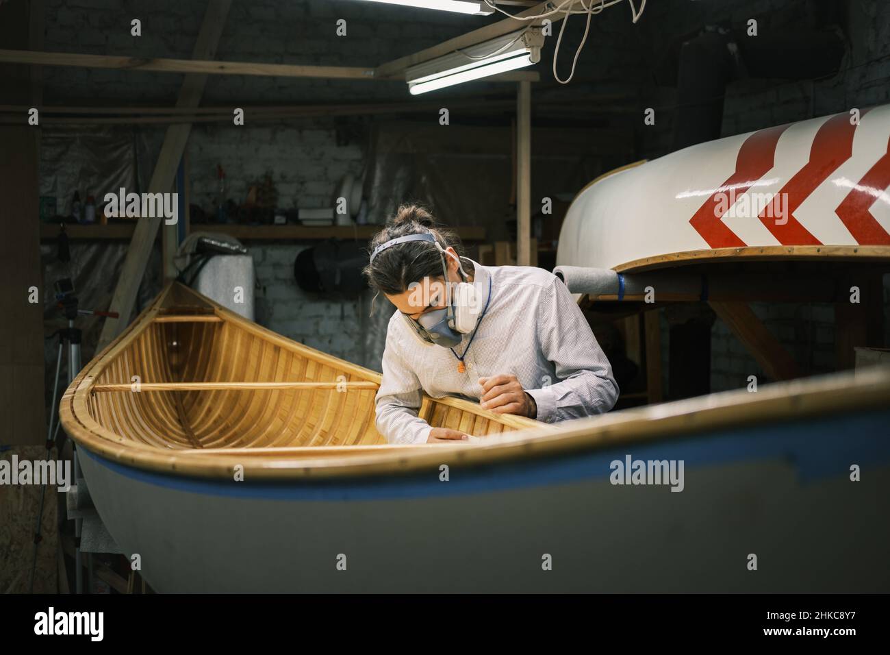 Kanubauer schleift das Boot in einer kleinen Werkstatt Stockfoto