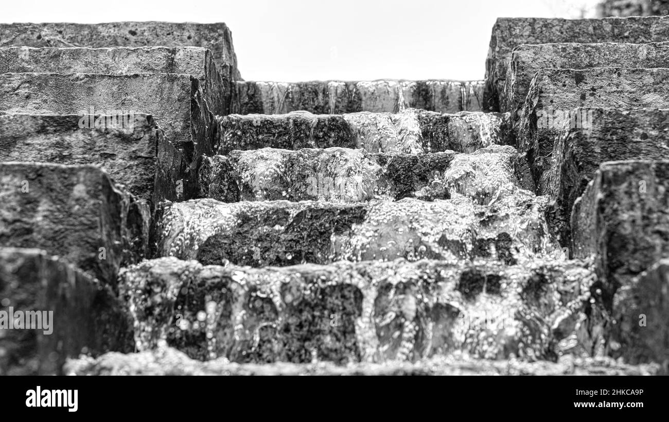Wasserfall über eine Steintreppe. Ein Bach, der durch einen Park fließt. Wasser tropft und fliegt durch die Luft. Stockfoto