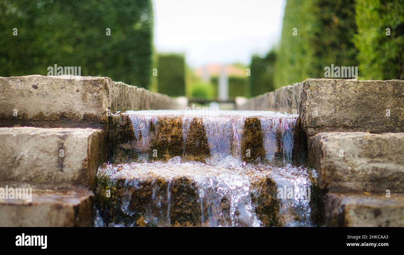 Wasserfall über eine Steintreppe. Ein Bach, der durch einen Park fließt. Wasser tropft und fliegt durch die Luft. Stockfoto